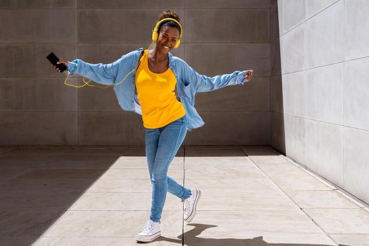 Una chica bailando con auriculares en la calle