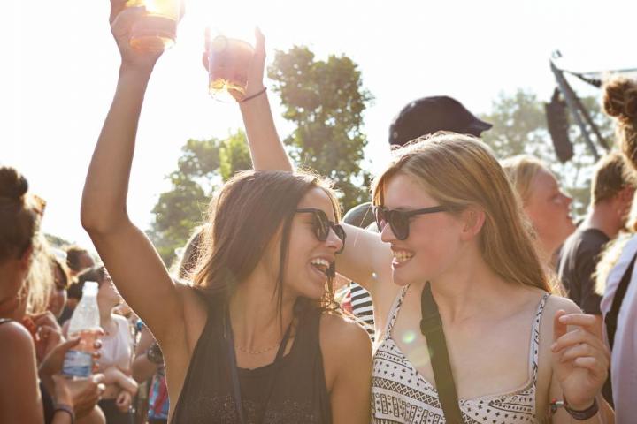 Dos chicas en un festival con su vaso arriba