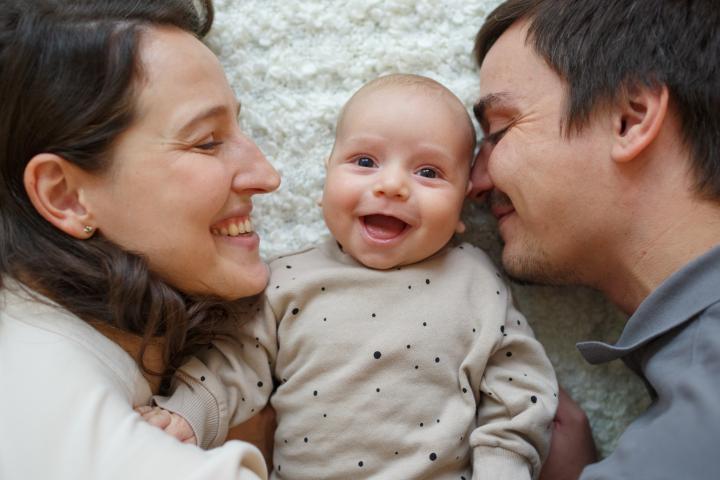 Madre, bebé y padre sonrientes.