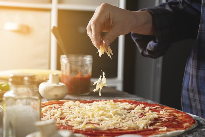 Una persona preparando una pizza.