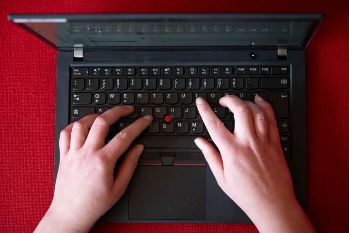 Una mujer que teletrabaja escribe en su portátil de empresa.