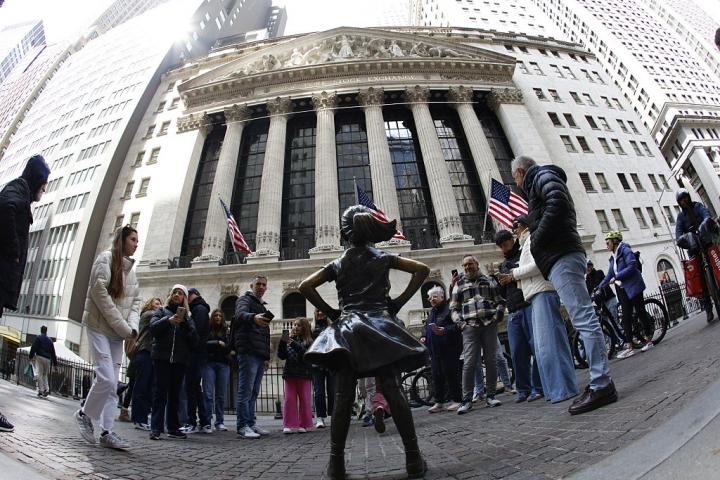 Un grupo de turistas rodea la escultura 'Niña Sin Miedo' de la uruguaya Kristen Visbal, instalada delante del edificio de Wall Street.