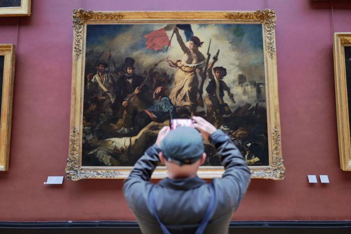 Un turista fotografía La Libertad guiando al pueblo, el cuadro de Eugène Delacroix en el Museo del Louvre