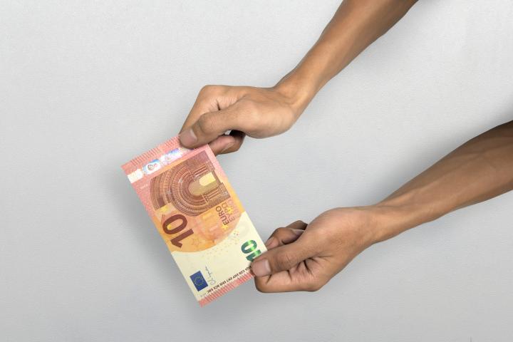 Imagen de una persona sosteniendo un billete de 10 euros.