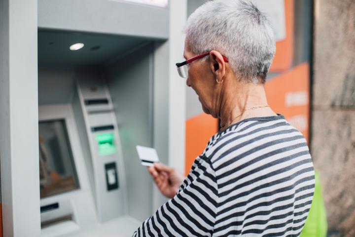 Una señora mayor sacando dinero en un cajero automático.