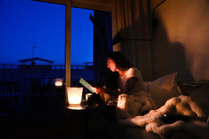 Una mujer lee en su casa con ayuda de una vela  en la localidad de El Masnou (Barcelona) durante el corte de suministro eléctrico.