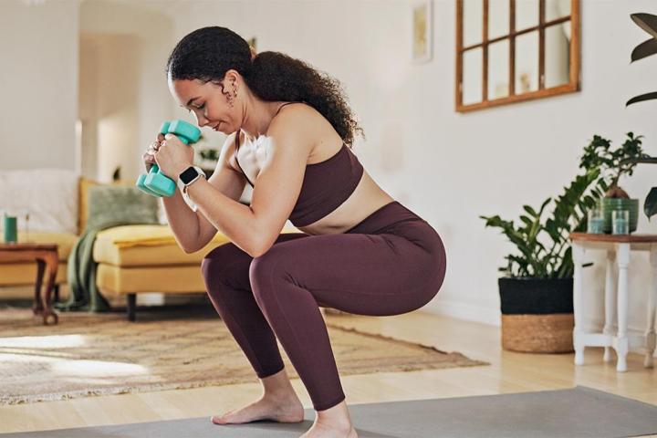 Una mujer con mancuernas entrenando en casa