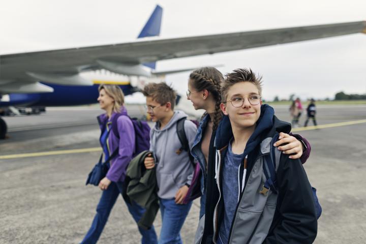 Imagen de archivo de adolescentes junto con una adulta bajando de un avión.