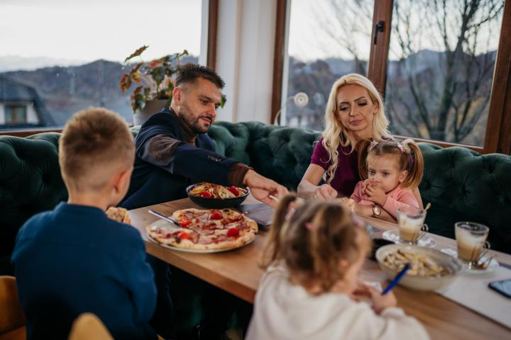 Padres comiendo en un restaurante con sus hijos.