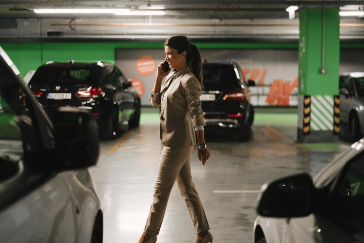 Imagen de una persona caminando en busca de su coche, en un garaje subterráneo, mientras conversa por teléfono.