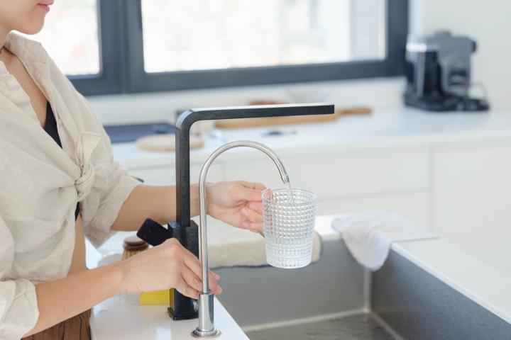 Imagen de archivo de una persona echándose agua del grifo.