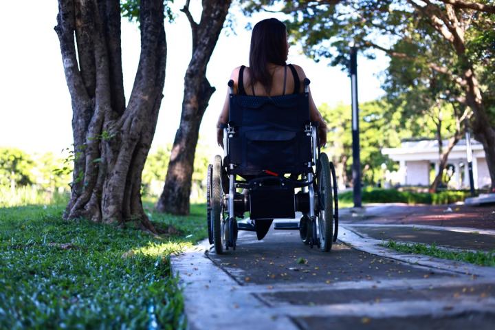Una mujer en silla de ruedas pasea por un parque.