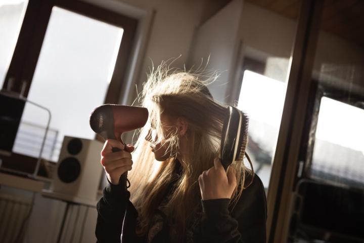 Una adolescente se seca el pelo en su casa.