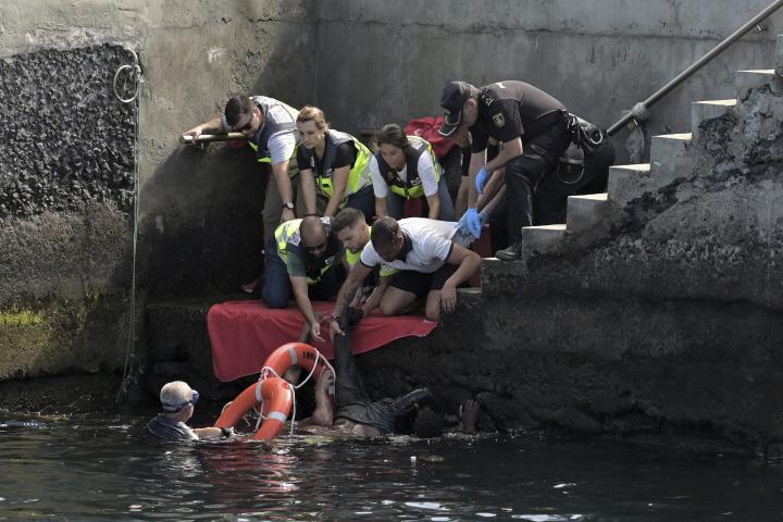 Personal de emergencias asiste a los ocupantes de un cayuco volcado en el puerto de La Restinga (El Hierro, Canarias), cuando iban a desembarcar.