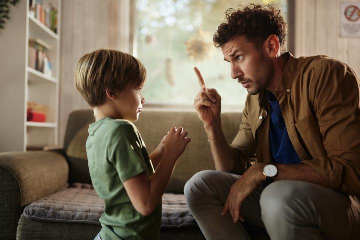 Un padre regaña a su hijo en la sala de estar.