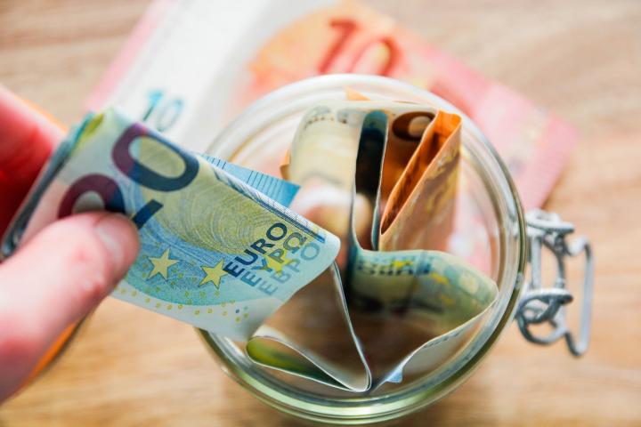 Una persona retira dinero de un bote de propinas.