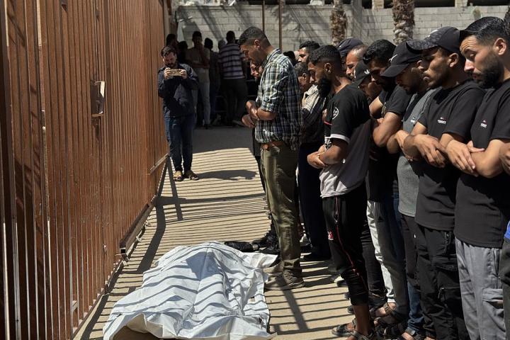 Un grupo de palestinos reza ante los cadáveres de las personas muertas en el reparto de ayuda.