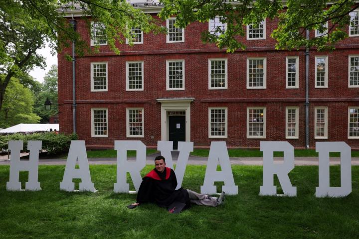Un estudiante de Harvard posa ante un cartel de la universidad estadounidense.