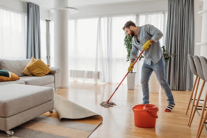 Un hombre fregando el salón de su casa.