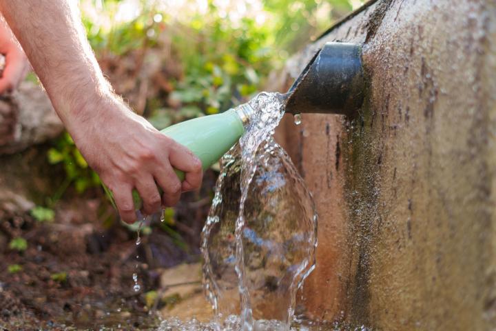 Una persona llenando de agua una botella de aluminio