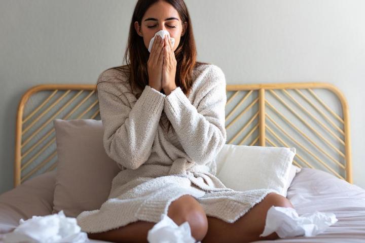 Una chica en la cama rodeada de pañuelos.