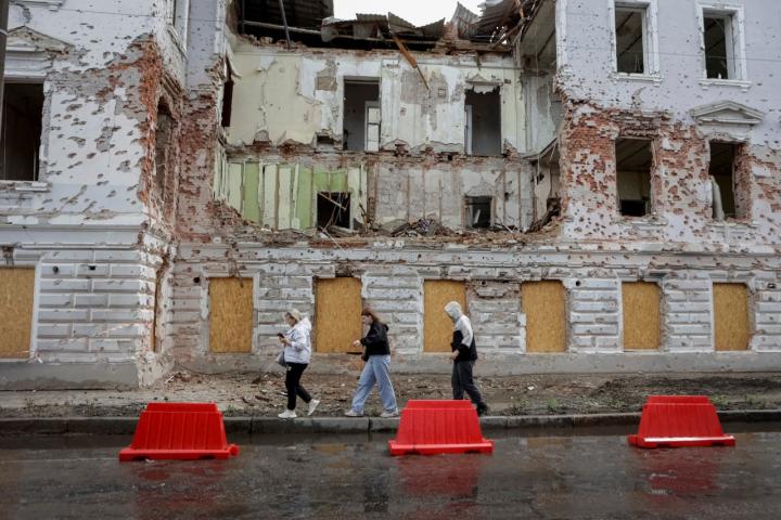 Vecinos de Sumy caminan por una calle cerca de un edificio dañado por los ataques con misiles rusos.