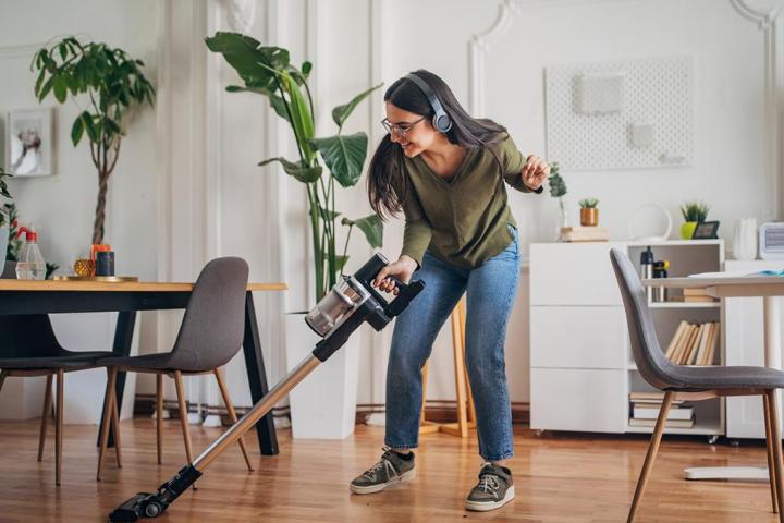 Una chica aspirando su casa mientras baila.