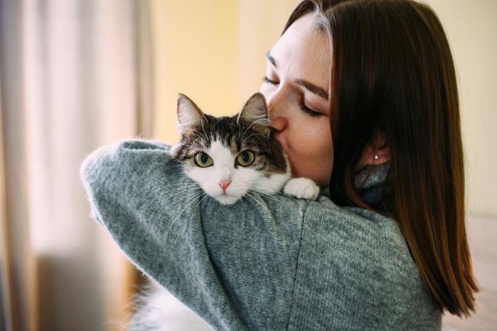 Una mujer dando un beso a su gato.