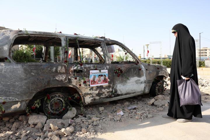 Una mujer iraní con velo, junto a una ambulancia de la Media Luna Roja destruida en un ataque de Israel.