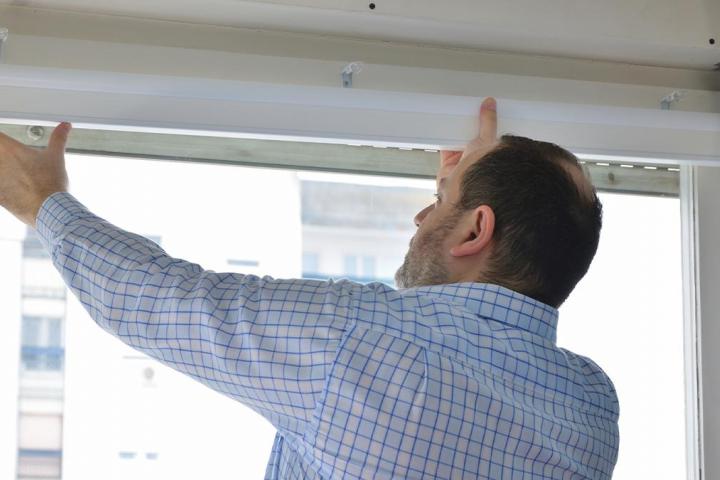Un hombre colocando una persiana.