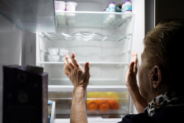 Una mujer mayor comprueba que no hay nada de comer en su nevera.
