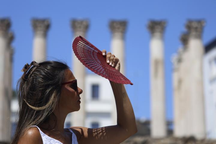 Una joven se tapa la cara con un abanico mientras camina por el centro de Córdoba, en plena ola de calor.