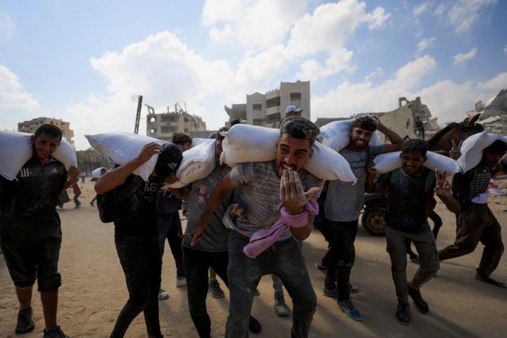 Un grupo de palestinos regresa a su campamento después de recoger ayudaen Beit Lahia.