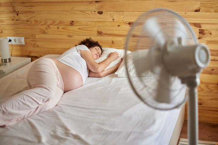 Una embarazada duerme frente al ventilador.