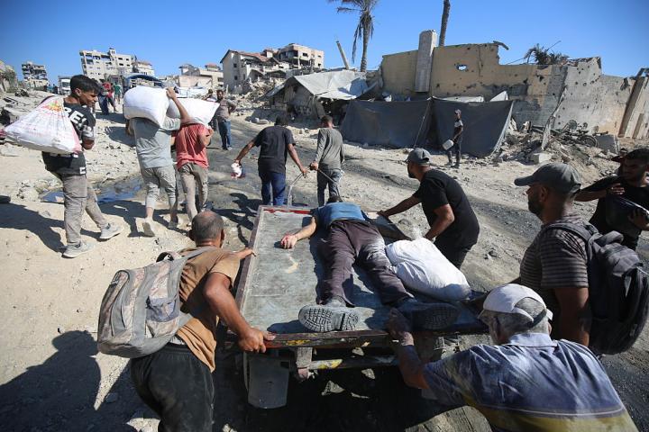 Un grupo de gazatíes traslada el cuerpo de un fallecido en las colas para pedir ayuda en Gaza.