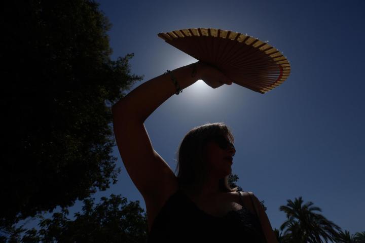 Una mujer se protege con un abanico del sol en Córdoba.