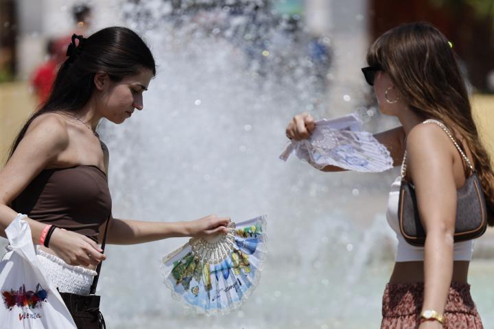 Dos mujeres se refrescan en el centro de València, durante la ola de calor de agosto de 2025.
