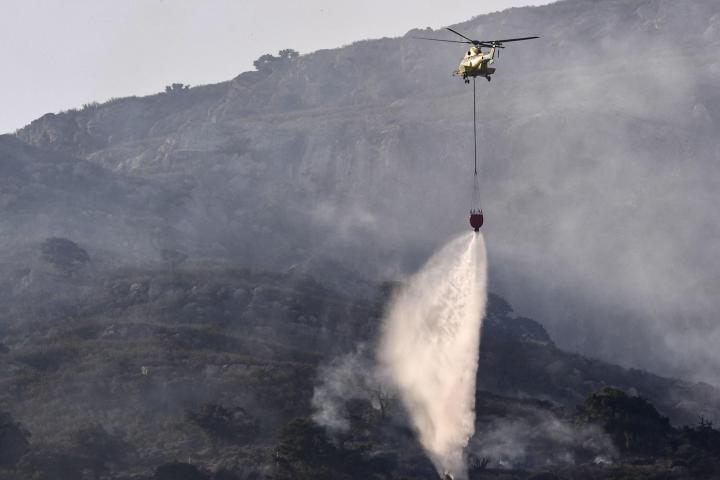 Un helicóptero trabaja en las labores de extinción del incendio que desde este lunes afecta a la Sierra de la Plata, en Tarifa (Cádiz).