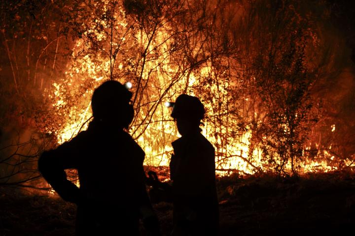 Bomberos forestales antes las grandes llamas del incendio en Aguasmestas, una parroquia del municipio de Quiroga, en la provincia de Lugo.