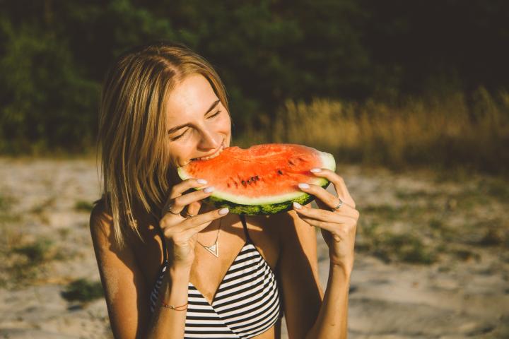 Una mujer comiendo sandía en playa, en una imagen de archivo.