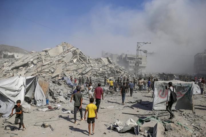 Palestinos caminan entre escombros mientras sale humo del edificio residencial al-Roya tras un ataque aéreo israelí en el oeste de la ciudad de Gaza, Franja de Gaza, el 8 de septiembre de 2025.