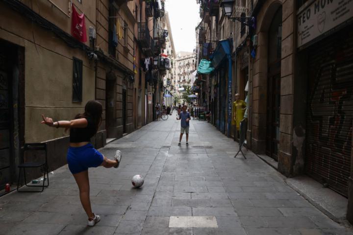 Dos niños juegan al fútbol en las calles de Barcelona.