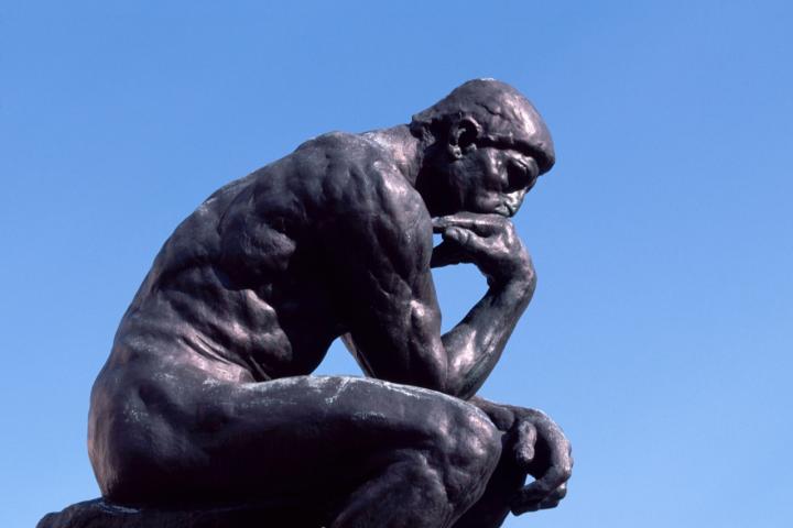 Escultura de El pensador de Rodin contra un cielo azul, símbolo de concentración y reflexión.