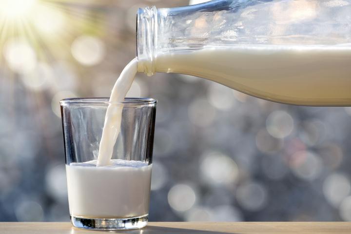 Una persona sirve un vaso de leche.