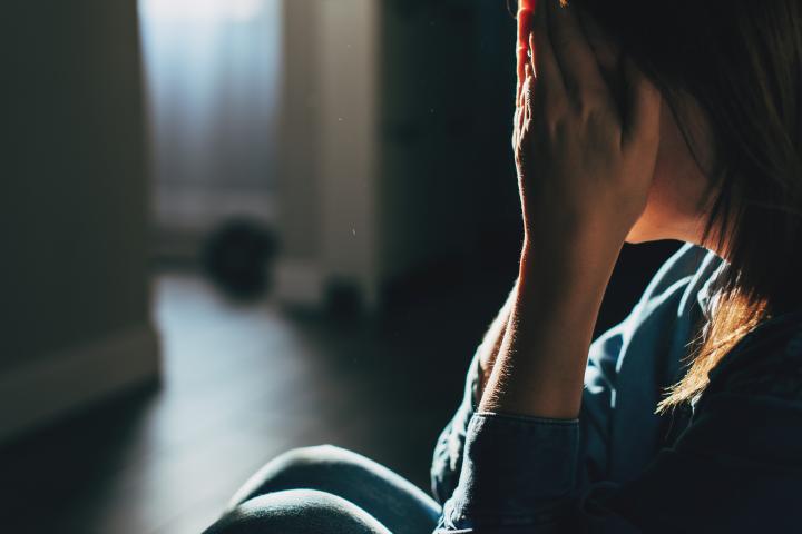 Ilustración de una silueta de una mujer en shock, con las manos en la cara, en el pasillo de una vivienda.