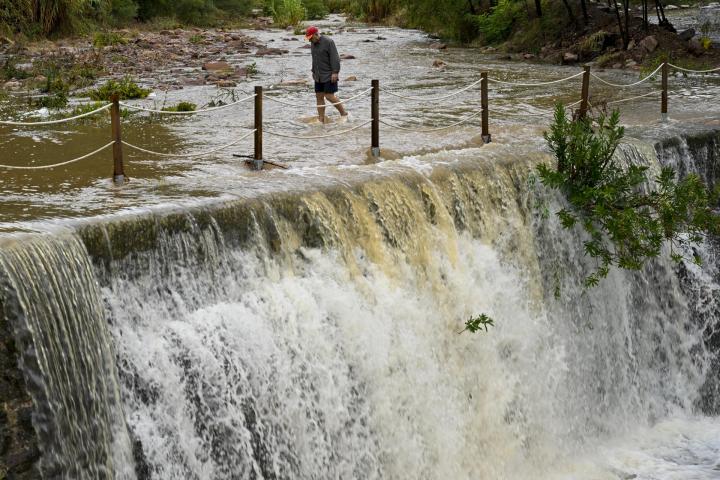 Un hombre cruza un badén inundable en Castellón.