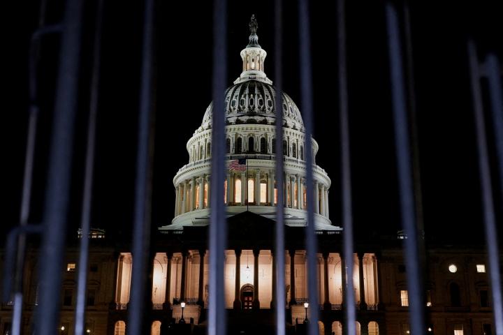 El Capitolio de Estados Unidos iluminada de noche, vista tras las rejas, antes del cierre de Gobierno en Washington.
