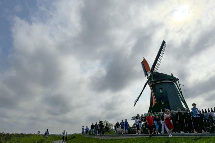 Turistas caminando frente a un molino de viento en Zaanse Schans, Holanda.