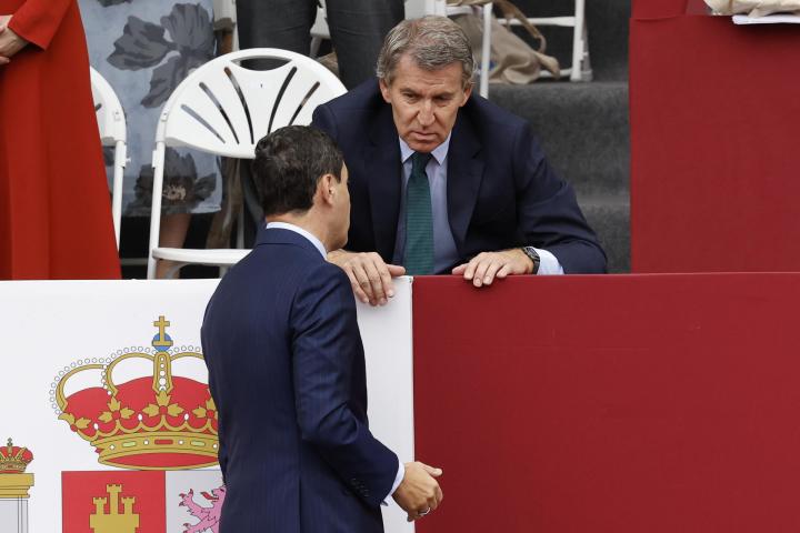 alt="alt="El líder del PP, Alberto Núñez Feijóo (d) conversa con el presidente de Andalucía, Juanma Moreno (i) antes del desfile de las Fuerzas Armadas con motivo de la Fiesta Nacional en la tribuna de autoridades este domingo. EFE/ Chema Moya""