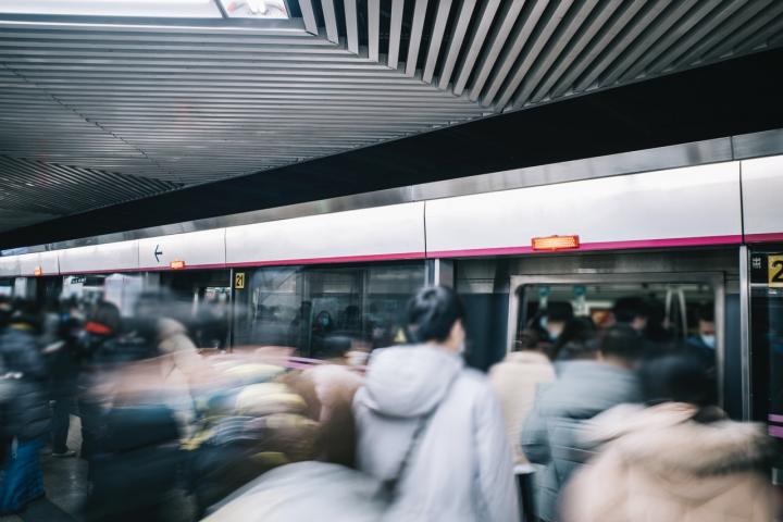 Andén del metro de Pekín con decenas de personas subiendo a un tren en hora punta.